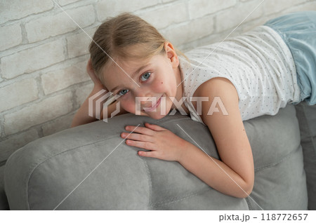 Caucasian little girl lying on the back of the sofa. Caucasian little girl lying on the back of the sofa. 118772657