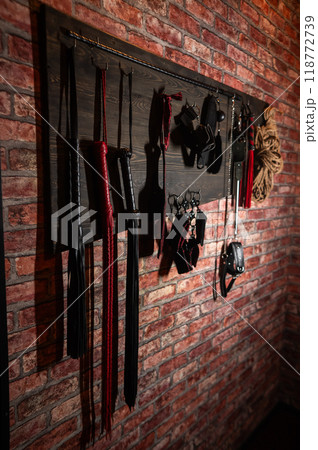 A set of BDSM equipment hanging on the wall. Vertical photo.  118772739
