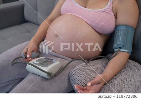 Close-up of the belly of a pregnant woman measuring blood pressure with a tonometer. Hypotension.  118772886