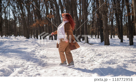 Portrait of an excited red-haired curly fat woman in the park in winter. Portrait of an excited red-haired curly fat woman in the park in winter. 118772958