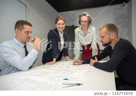Designers engineers at a meeting discuss working drawings.  118773059