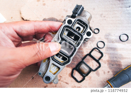 A mechanic is replacing a worn out rubber seal to repair a car engine part A mechanic is replacing a worn out rubber seal to repair a car engine part 118774932