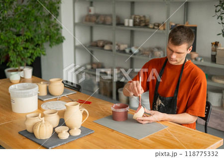 Potter paints ceramic dishes with a brush.  118775332