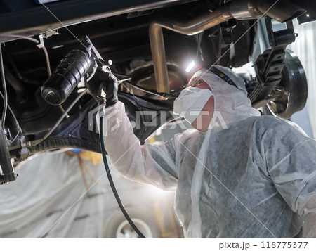 The master sprays an anti-corrosion compound on the bottom of the car. The master sprays an anti-corrosion compound on the bottom of the car. 118775377