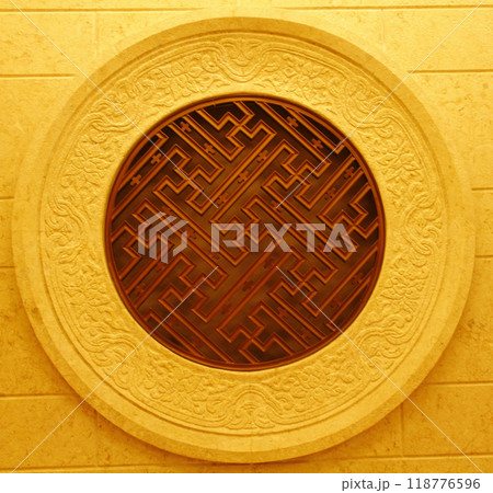 An ornate vintage round Chinese window, showcasing intricate patterns and a dark oval centerpiece to Represents ancient local wisdom. Image for Cultural artwork content. An ornate vintage round Chinese window, showcasing intricate patterns and a dark oval centerpiece to Represents ancient local wisdom. Image for Cultural artwork content. 118776596