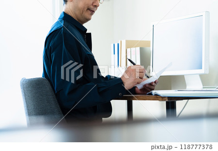 パソコン操作をする作業服のミドル男性 118777378