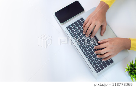 Office desk clean and minimal working scene with businesswoman hands over a silver laptop keyboard on a white office table in workplace, Top view, Copy space. 118778369