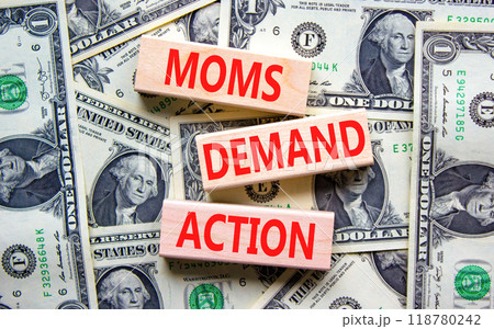 Moms demand action symbol. Concept words Moms demand action on wooden blocks on a beautiful background from dollar bills. Business, finacial and Moms demand action concept. 118780242