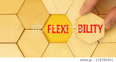 Flexibility symbol. Concept word Flexibility on beautiful wooden puzzles. Beautiful yellow background. Businessman hand. Business flexibility concept. Copy space. Flexibility symbol. Concept word Flexibility on beautiful wooden puzzles. Beautiful yellow background. Businessman hand. Business flexibility concept. Copy space. 118780361
