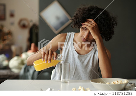 Teenage guy having breakfast after booze 118781282