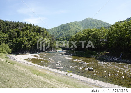 新緑が美しい山並みと清流 遠くに吊り橋が見える 118781338