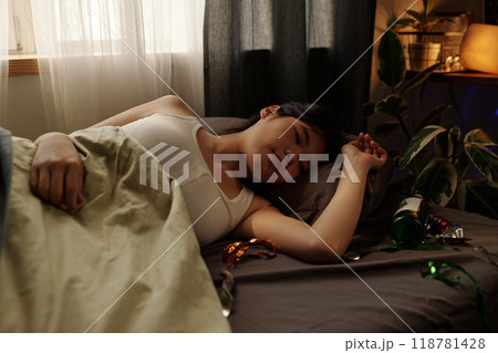 Young woman with hangover lying on bed 118781428