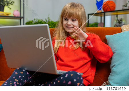 Preteen child girl looking at laptop camera, making video webcam conference call with friends family 118781659