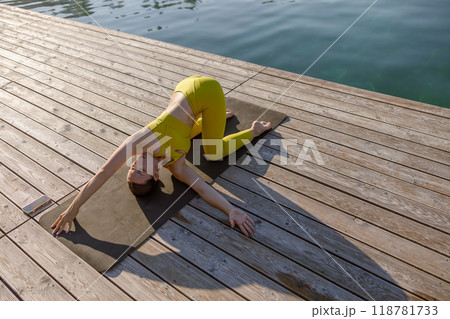 Engaging in a serene Yoga Pose by Waters Edge promotes tranquility, harmony and balance 118781733