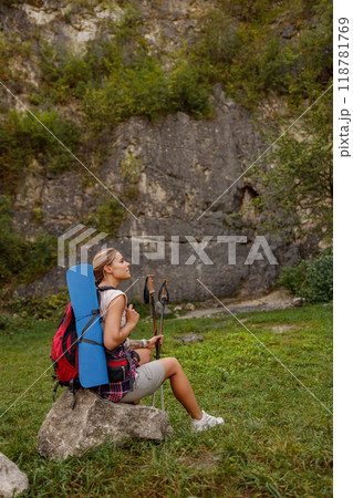 A Young Hiker is Taking a Rest on a Rock in the Beautiful and Scenic Nature Around Him 118781769