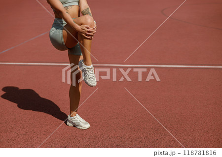 An athletic woman is stretching on a sunny track, embodying empowerment and energy 118781816