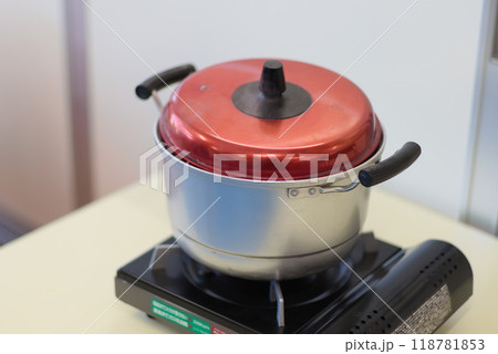 カセットコンロを使い鍋を沸騰させているシーン 118781853