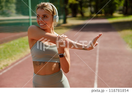 A Young Woman Engaged in a Stretching Routine Outdoors While Dressed in Athletic Gear A Young Woman Engaged in a Stretching Routine Outdoors While Dressed in Athletic Gear 118781854