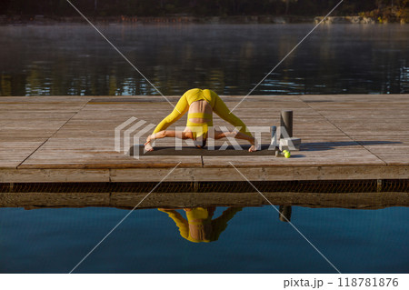 Engaging in Yoga Practice at Sunrise while being alongside the serene Waters edge Engaging in Yoga Practice at Sunrise while being alongside the serene Waters edge 118781876