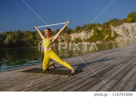 Engaging in a Dynamic Yoga Practice by the Water while Dressed in Bright Yellow Fitness Attire Engaging in a Dynamic Yoga Practice by the Water while Dressed in Bright Yellow Fitness Attire 118781886