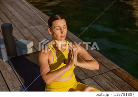 A Woman Practicing Yoga by the Water in a Beautiful Yellow Outfit Enjoying Nature A Woman Practicing Yoga by the Water in a Beautiful Yellow Outfit Enjoying Nature 118781887