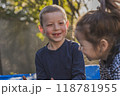 A boy and a girl happily sitting on a trampoline together outdoors 118781955