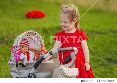 little girl plays with a doll and a stroller 118781962