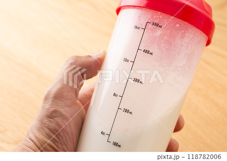 シェイカーに入ったプロテインドリンクを持つ手元 118782006