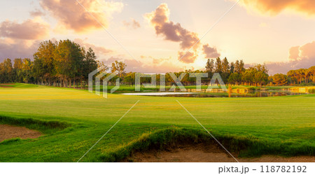 Picturesque panoramic view of golf course with bunker. Golf course at sunset with beautiful sky Picturesque panoramic view of golf course with bunker. Golf course at sunset with beautiful sky 118782192