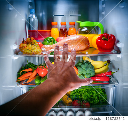Human hands reaching for turkey leg food at night in the open refrigerator Human hands reaching for turkey leg food at night in the open refrigerator 118782241