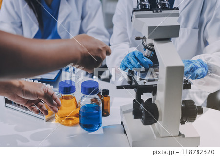 Scientist using microscope in laboratory. Close-up of a researcher's hands adjusting a modern microscope in a lab setting. Science concept Scientist using microscope in laboratory. Close-up of a researcher's hands adjusting a modern microscope in a lab setting. Science concept 118782320