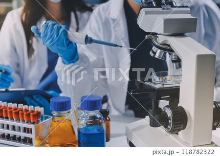 Scientist using microscope in laboratory. Close-up of a researcher's hands adjusting a modern microscope in a lab setting. Science concept 118782322