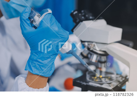 Scientist using microscope in laboratory. Close-up of a researcher's hands adjusting a modern microscope in a lab setting. Science concept Scientist using microscope in laboratory. Close-up of a researcher's hands adjusting a modern microscope in a lab setting. Science concept 118782326