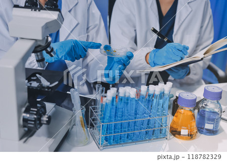 Scientist using microscope in laboratory. Close-up of a researcher's hands adjusting a modern microscope in a lab setting. Science concept 118782329