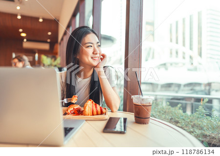 Asian woman at cafe with laptop sitting looking out through window city people modern lifestyles Asian woman at cafe with laptop sitting looking out through window city people modern lifestyles 118786134