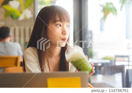 Young adult business southeast asian woman with long hair drinking matcha at indoor cafe on day 118786761