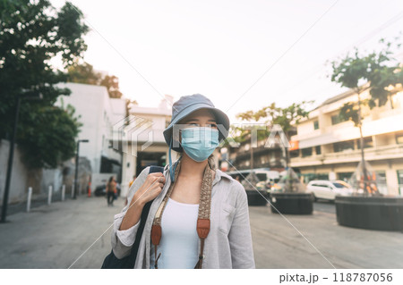 Walking young adult asian woman traveller wear face mask for covid-19 traveling in local city on summer day Walking young adult asian woman traveller wear face mask for covid-19 traveling in local city on summer day 118787056