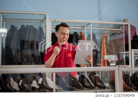 leather shoe salesman holding tablet with fist pump gesture leather shoe salesman holding tablet with fist pump gesture 118789049