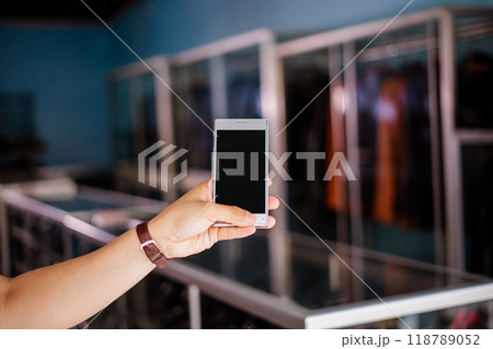 blurred and cropped view of hand holding phone at leather shoes store blurred and cropped view of hand holding phone at leather shoes store 118789052