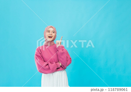 A Joyful Young Woman in a Stylish Pink Sweater Posing Against a Bright Blue Background Photo A Joyful Young Woman in a Stylish Pink Sweater Posing Against a Bright Blue Background Photo 118789061