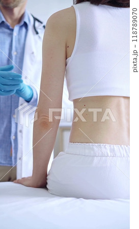 Doctor and patient. Physician putting on blue gloves is ready to examine female patient in clinic. Orthopedics in medicine Doctor and patient. Physician putting on blue gloves is ready to examine female patient in clinic. Orthopedics in medicine 118789070