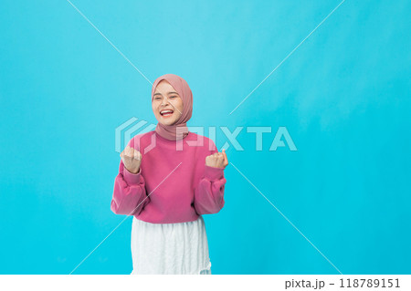 A young woman in casual style and fashionable accessories poses against a bright blue background 118789151