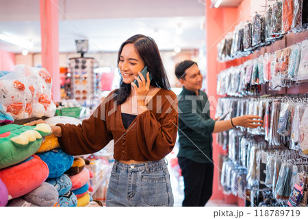 female buyer selects doll during a call using mobile phone female buyer selects doll during a call using mobile phone 118789719