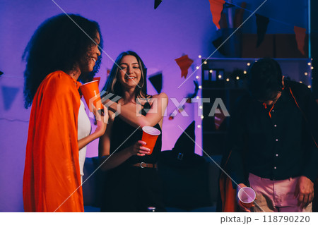 Joyful office Halloween party with coworkers in costumes, celebrating with drinks and laughter, fostering teamwork and festive spirit 118790220