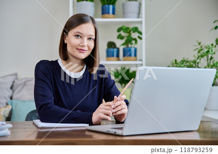 Portrait of young woman at her workplace at desk with laptop, looking at camera 118793259