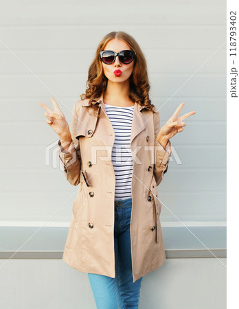 Fashion pretty young woman blowing kiss wearing a black sunglasses coat over grey background Fashion pretty young woman blowing kiss wearing a black sunglasses coat over grey background 118793402