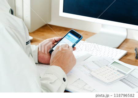 スマホを操作する作業服の男性 スマホを操作する作業服の男性 118796582