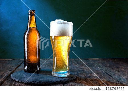 A bottle of cold beer. A glass of cold beer. Beer on the table. Serving beer on a tray. Drops on glass. A bottle of cold beer. A glass of cold beer. Beer on the table. Serving beer on a tray. Drops on glass. 118798665