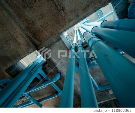 A bright blue pipes attached to a solid concrete wall A bright blue pipes attached to a solid concrete wall 118803363