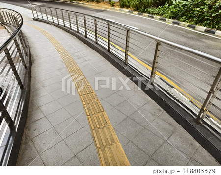 Curved path with guardrail and yellow line for blind people along the road Curved path with guardrail and yellow line for blind people along the road 118803379